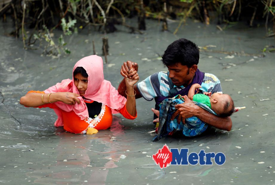 Pelarian Rohingya membawa anak mereka melintas sempadan di Sungai Naf, Teknaf, Bangladesh, semalam. FOTO Reuters 