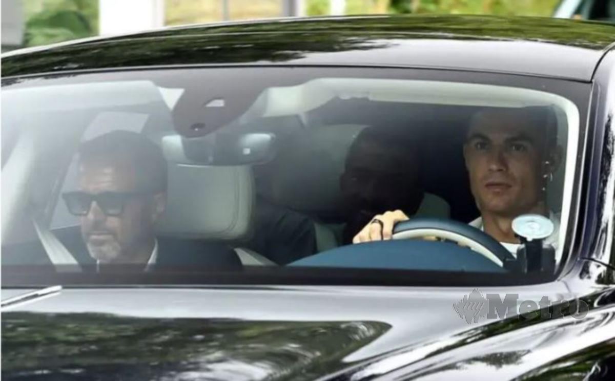 CRISTIANO Ronaldo (kiri) memandu kereta ketika tiba di Carrington bersama Mendes, semalam. FOTO Agensi