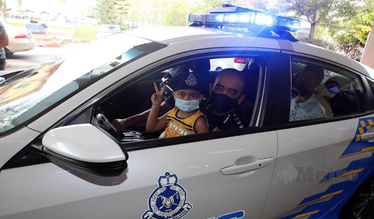 NOORZAINY meriba Muhammad Firash Arryan yang menghidap penyakit leukemia menaiki kereta peronda polis (MPV) pada majlis Sambutan Peringatan Hari Polis ke-214 peringkat IPD Seberang Perai Utara. FOTO Danial Saad