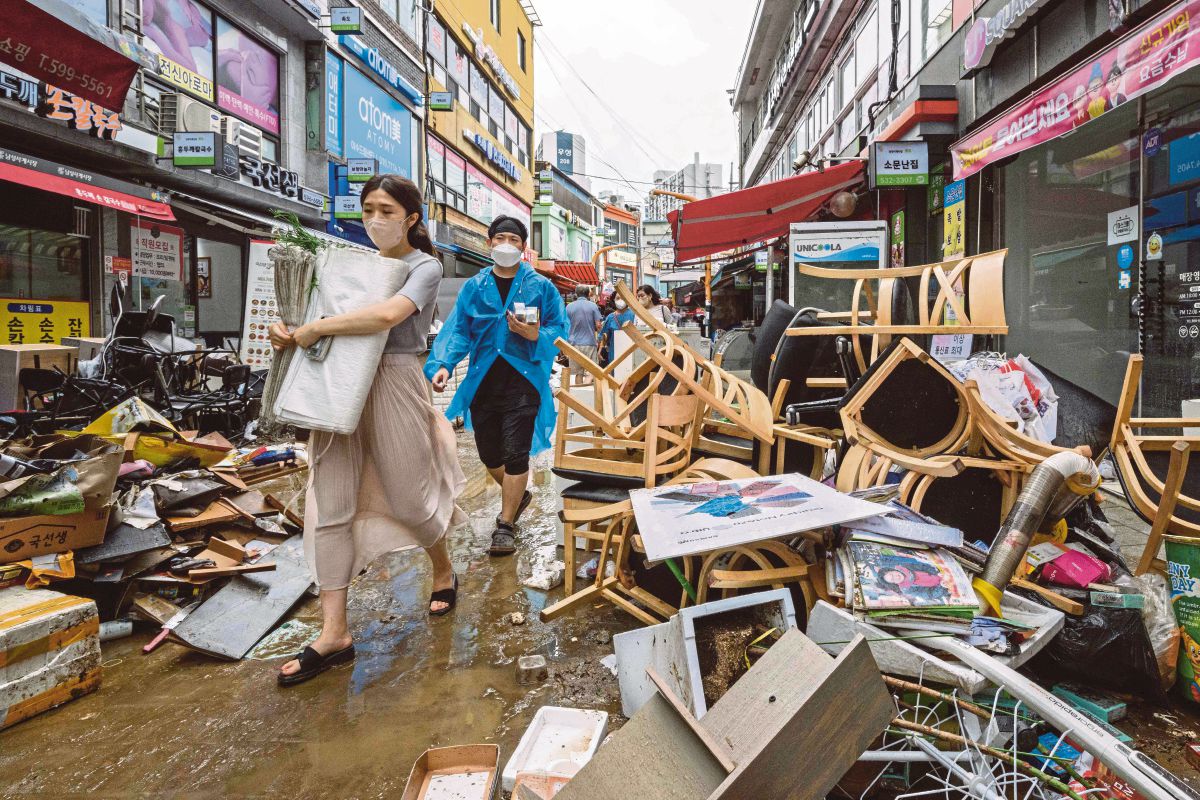 ORANG ramai berjalan melalui barangan yang rosak akibat banjir buruk di daerah Gangnam, Seoul. FOTO AFP 