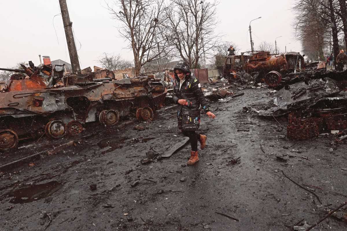 WANITA Ukraine berjalan melepasi aset tentera Rusia yang rosak atau musnah di Bucha, Ukraine. FOTO EPA 