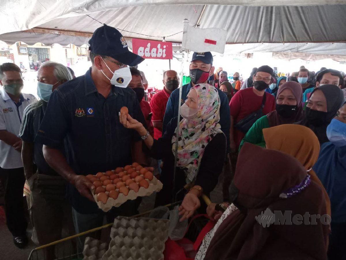 ROSOL (kiri) melihat beberapa papan telor ayam dibeli pengunjung PJKM Kuala Ping, Kuala Berang, hari ini. FOTO BAHAROM BAKAR