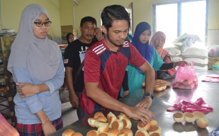 ANAK ketiga, Mohd Arif Helmi (tengah) tidak menang tangan membantu Mokhtar menjual roti pada musim cuti.