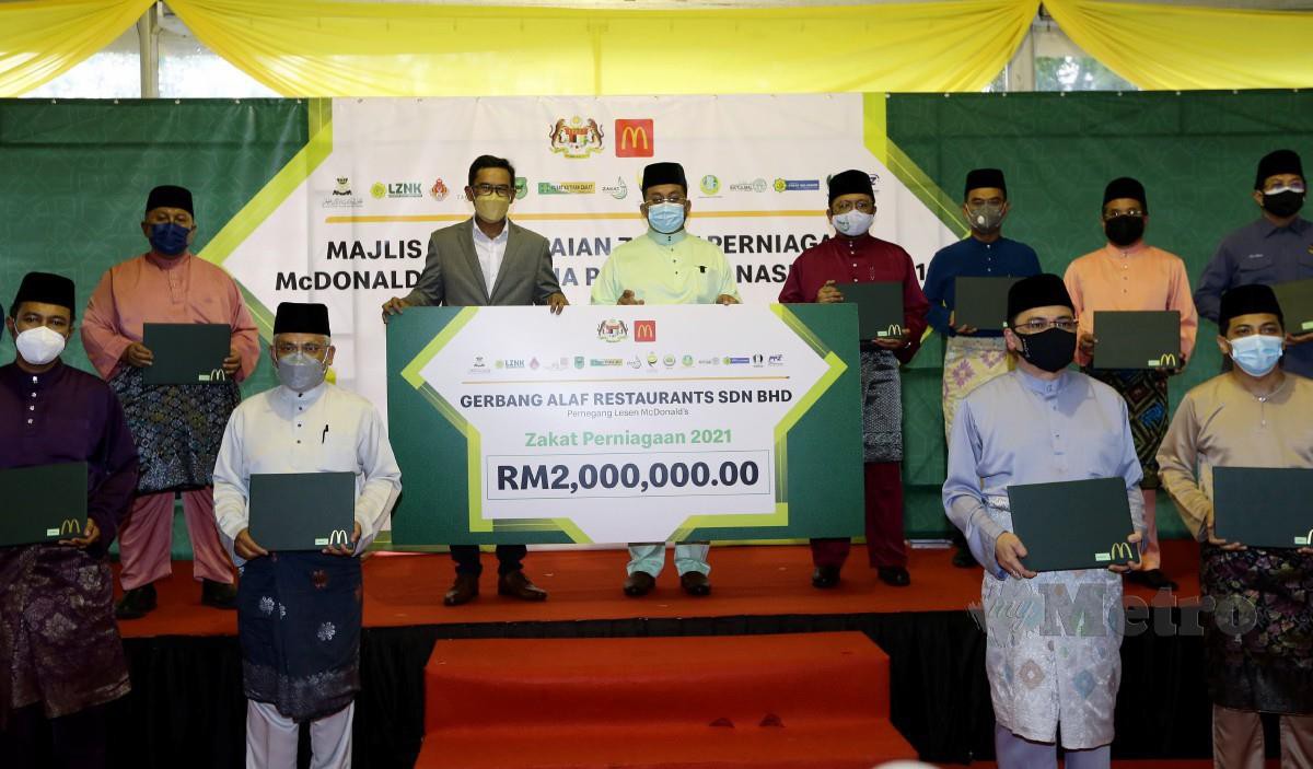 Ahmad Marzuk (belakang tiga kiri) bergambar bersama Azmir Jaafar (belakang dua kiri) dan wakil-wakil majlis agama islam negeri ketika majlis penyampaian zakat perniagaan oleh McDonald's Malaysia di Putrajaya. FOTO MOHD FADLI HAMZAH