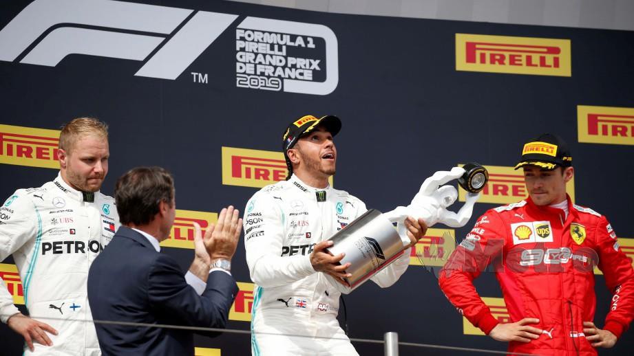 Hamilton (tengah) bersama trofi kejuaraan di podium disaksikan Bottas (kiri) dan Leclerc. FOTO REUTERS