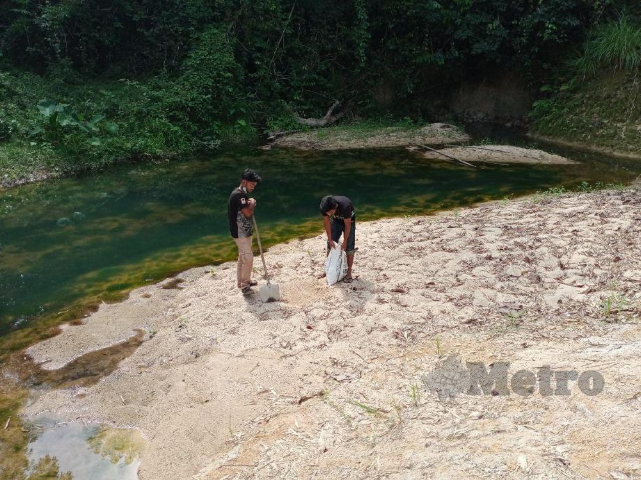 MOHD Hakim (kiri) dan Mohd Haizu mengangkut pasir sungai untuk membuat batu-bata. FOTO Nor Amalina Alias