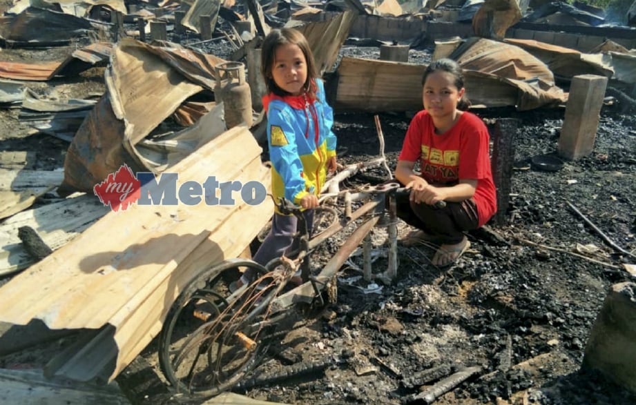 NOR Izati (kanan) bersama Nor Ain Hawani melihat basikal miliknya yang hangus dalam kebakaran membabitkan 12 pintu rumah kongsi pekerja kilang papan di Kawasan Industri Gua Musang, hari ini. FOTO Ramli Ibrahim. 