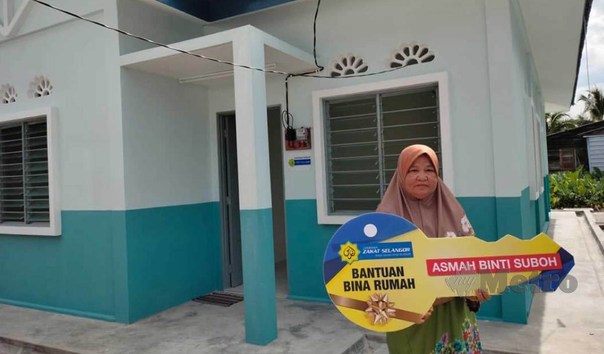 ASMAH bergambar bersama rumah baharu yang diterima pada Majlis Serahan Kunci Bantuan Bina Rumah LZS di Kampung Baru Pasir Penambang, Kuala Selangor. FOTO Amirul Aiman Hamsuddin