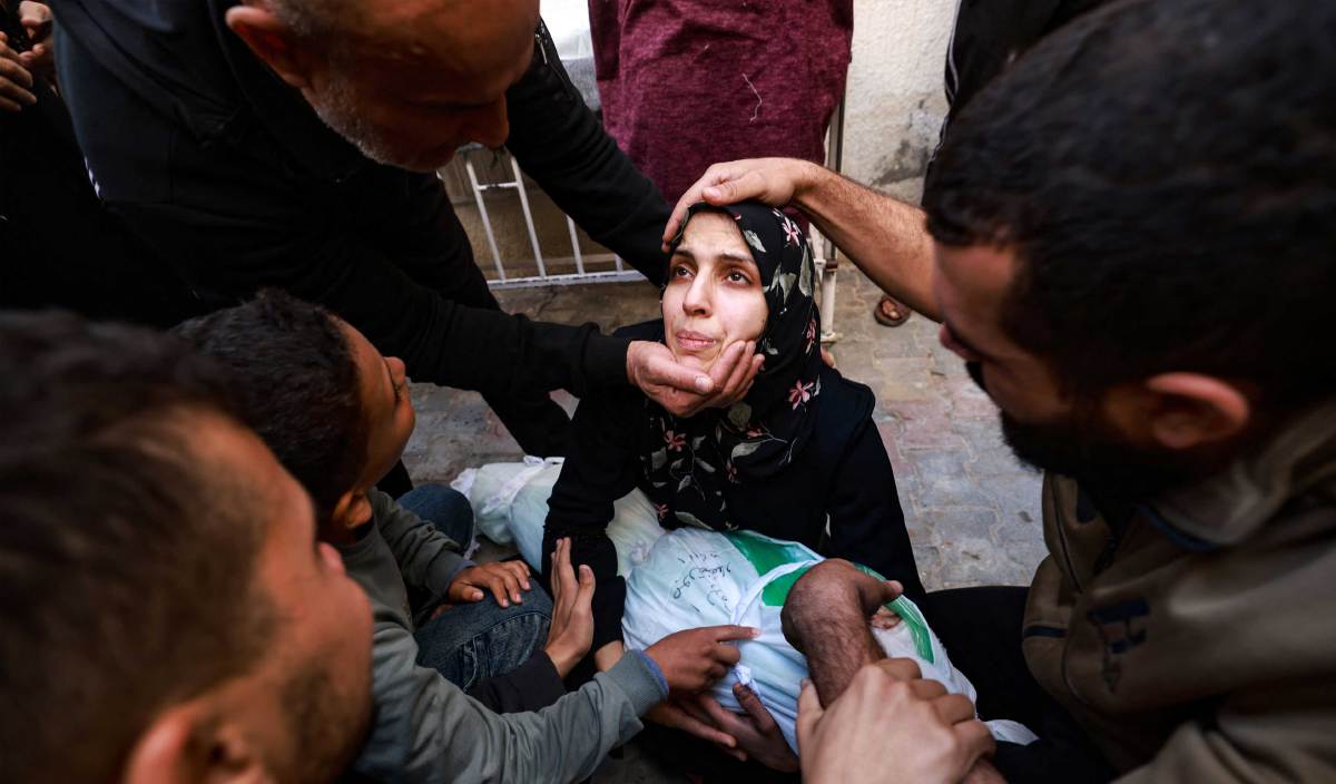 SEORANG wanita memeluk bayinya yang terbunuh dalam serangan udara rejim Zionis ditenangkan penduduk Palestin di Rafah, Semenanjung Gaza. FOTO AFP