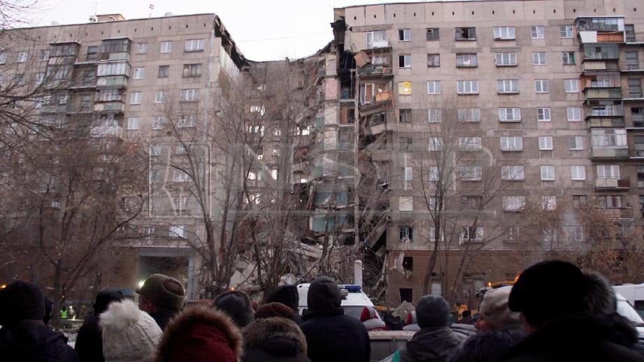 Orang ramai melihat pasukan penyelamat Russia membersihkan runtuhan selepas berlaku letupan gas di bangunan pangsapuri di Magnitogorsk. FOTO EPA  