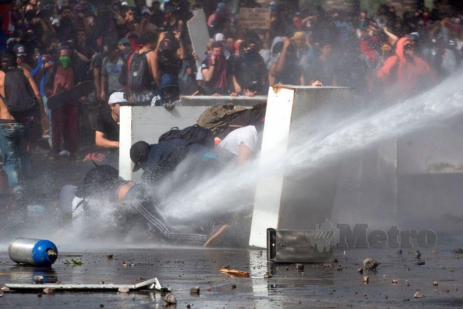 PENUNJUK perasaan bertempur dengan polis pada hari kelima bantahan di Santiago, Chile, hari ini. FOTO AFP
