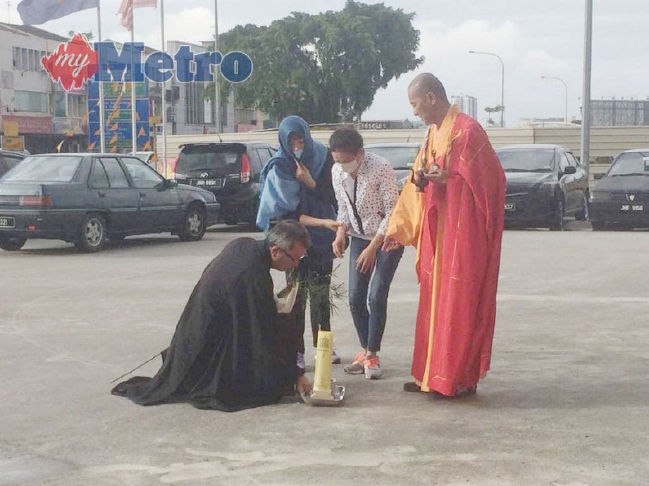 Isteri mangsa (baju putih) yang juga warga negara Vietnam berusia lingkungan 20-an menjalankan upacara keagamaan di stesen minyak di Jalan Sri Pelangi, Taman Pelangi, Johor Bahru, hari ini. FOTO NURUL AMANINA SUHAINI