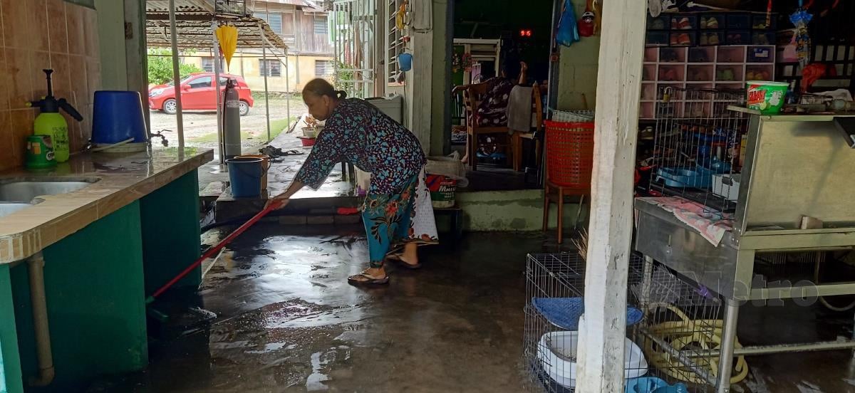Saadiah membersih rumahnya selepas dilanda banjir malam tadi di Kampung Bendang Sera, Baling. FOTO SAFURI KAMARUDIN