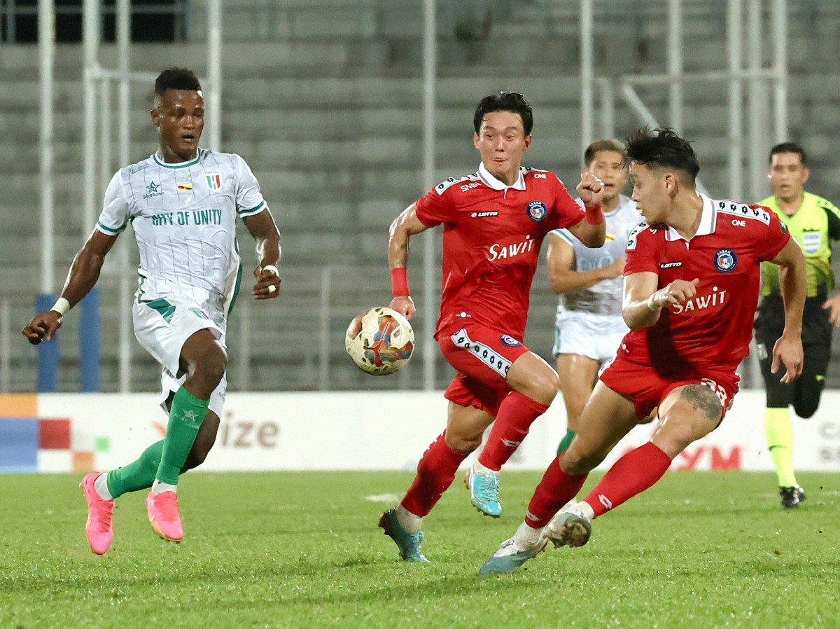 PEMAIN Kuching City FC, Abu Kamara cuba melepasi dua pemain Sabah FC pada saingan Piala Malaysia di Stadium Negeri hari ini. FOTO BERNAMA