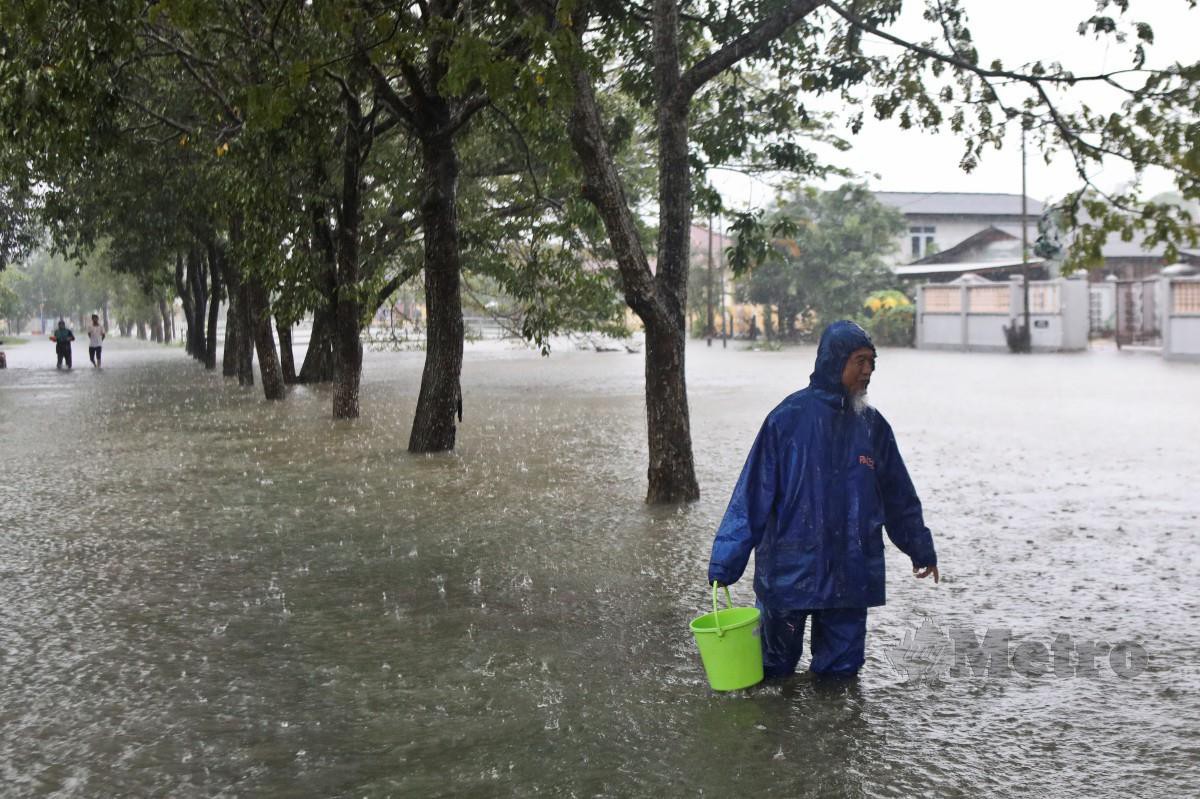 PENDUDUK berjalan meredah banjir  di Kampung Gong Tok Nasek selepas hujan lebat sejak malam tadi.  FOTO GHAZALI KORI