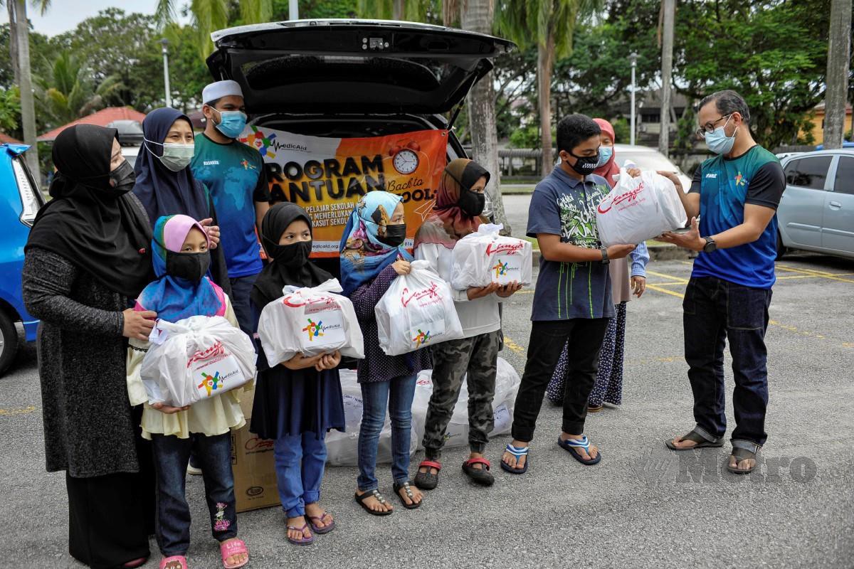Dr Syariz menyampaikan sumbangan bantuan persekolahan kepada penerima yang kurang bernasib baik pada Program Bantuan Back To School khas untuk pelajar sekolah rendah anjuran MedicAid di Bandar Tun Razak, Kuala Lumpur. FOTO AIZUDDIN SAAD