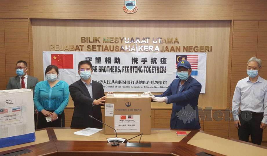 SAFAR (dua dari kanan) menerima sekotak topeng muka sebagai simbolik penyerahan bekalan perubatan sempena Majlis Penyerahan Sumbangan Konsulat China Kepada Kerajaan Sabah di Kota Kinabalu. FOTO Yun Mikail