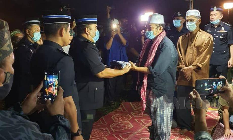 FADZIL (tiga dari kiri) menyerahkan Panji Sang Saka Biru kepada Muhammad Ismail di Tanah Perkuburan Islam Kampung Bakar Bata, Tanjung Rambutan, Perak, hari ini. FOTO ihsan polis.
