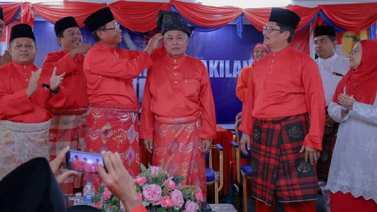 AHMAD dipakaikan tengkolok ketika merasmikan Mesyuarat Perwakilan Umno Bahagian Kemaman di sini, hari ini.
