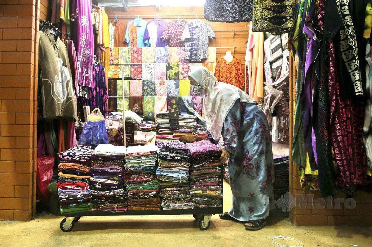 Salimah menyusun pakaian selepas premisnya dibenarkan beroperasi semula di Pasar Payang. FOTO GHAZALI KORI
