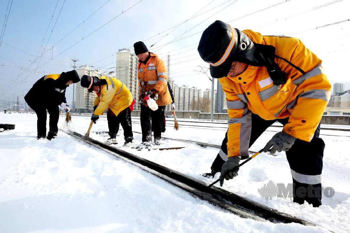 Pekerja membersihkan ais di landasan kereta api. FOTO Agensi 