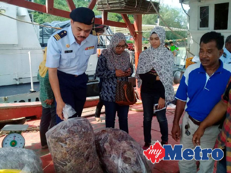 Pengarah Pengkalan Maritim Kemaman, Leftenan Komander Maritim Muhamad Rezal Kamal Bashah (kiri) memeriksa sotong yang dikering diatas bot nelayan yang ditahan di Pengkalan Maritim APMM Teluk Kalong. FOTO SHAMSUDIN HUSIN.
