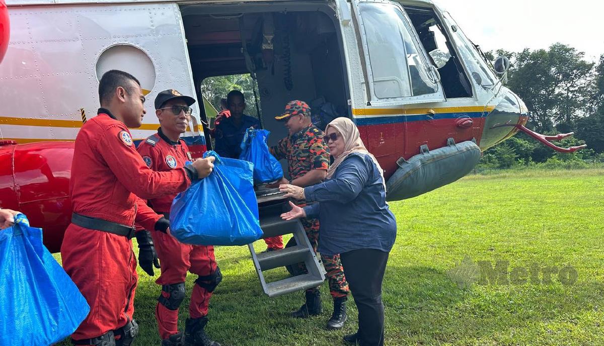Timbalan Menteri KKDW, Datuk Rubiah Wang (kanan) menyampaikan bantuan makanan kepada penduduk Orang Asli di Kampung Jader, Pos simpor, di sini. FOTO Paya Linda Yahya 