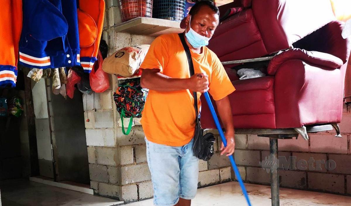 SAMY Murat membersihkan rumahnya di Kampung Betong Kanowit di Serian yang dilanda banjir ketiga sejak Rabu lalu. FOTO Mohd Roji Kawi