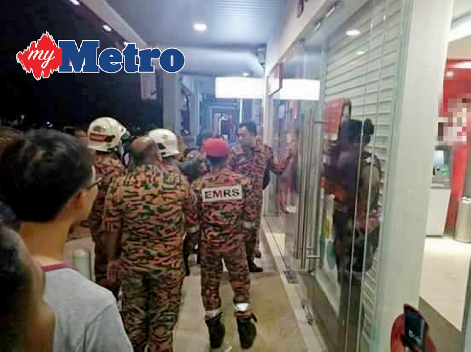 ANGGOTA bomba dan polis cuba menenangkan mangsa yang terperangkap antara dua pintu kaca dan pintu keselamatan sebuah bank di Selayang Jaya, awal pagi semalam. -Foto IHSAN PEMBACA