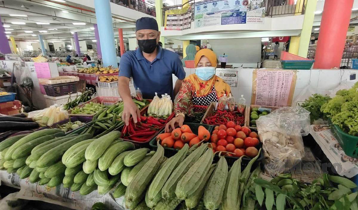 MOHD Afandi dan isterinya, Che Nga menunjukkan antara sayur-sayuran yang dijual di kedainya di Pasar Tasek Raja. FOTO Syaherah Mustafa