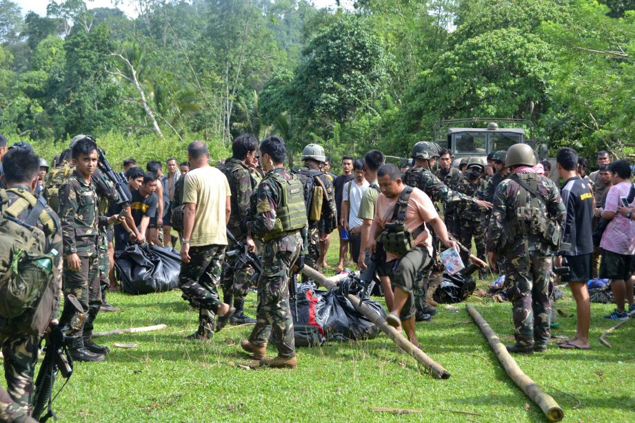 Tentera Filipina mengumpulkan beg mengandungi mayat anggota kumpulan Abu Sayyaf yang berjaya dibunuh di Bongkaong dekat pekan Patikul, Sulu, hari ini. - Foto AFP