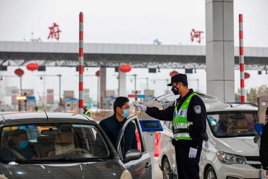 ANGGOTA polis memeriksa suhu badan pemandu di lebuh raya di Wuhan, wilayah Hubei. FOTO AFP