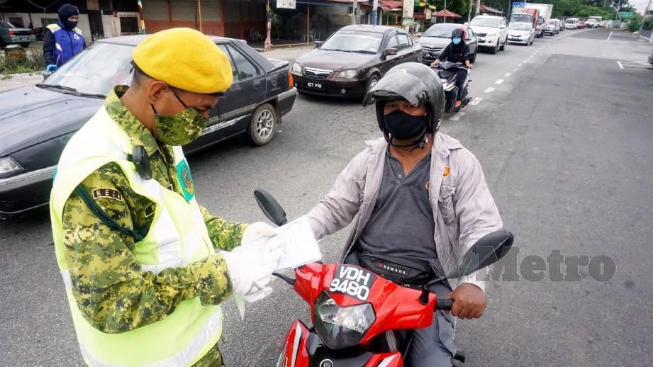 ANGGOTA Jabatan Sukarelawan Malaysia (RELA) memeriksa dokumen penunggang motosikal yang melalui sekatan jalan raya ketika pelaksanaan Perintah Kawalan Pergerakan (PKP) fasa ketiga. FOTO NSTP
