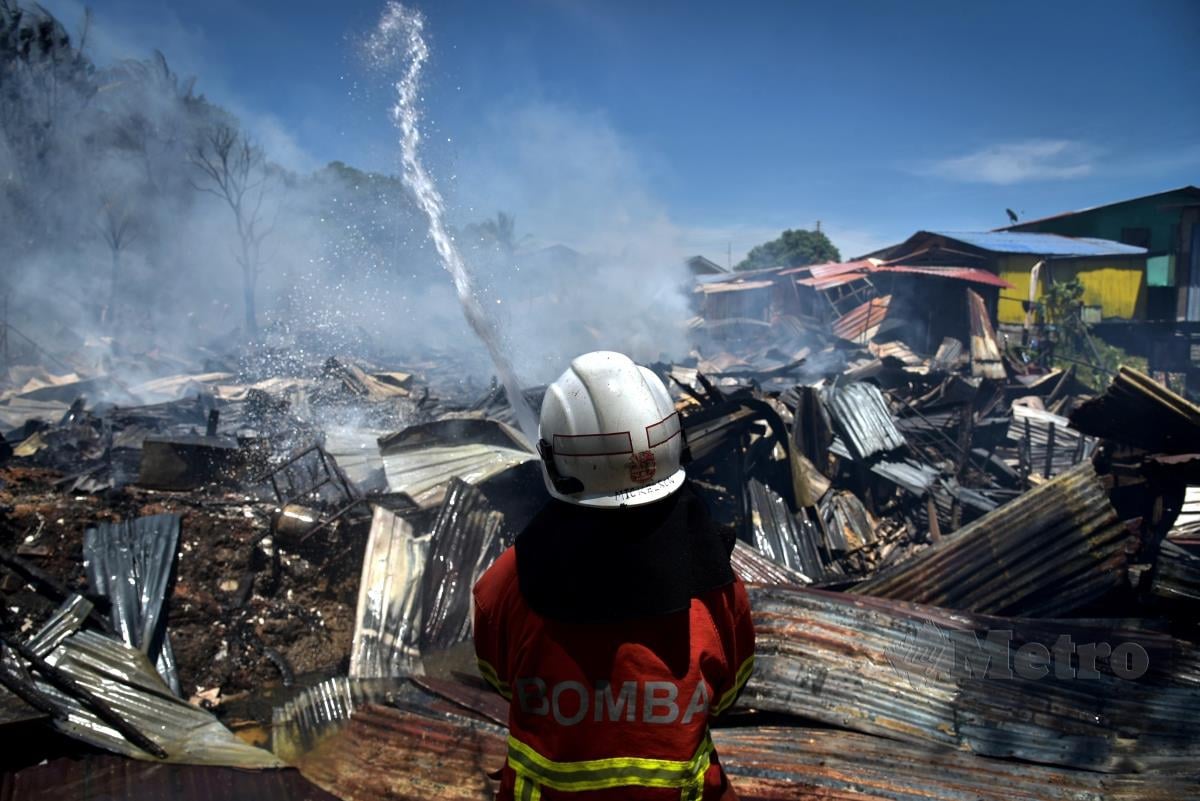 Anggota Jabatan Bomba dan Penyelamat Labuan bertungkus lumus memadamkan kebakaran dalam kejadian di Kampung Batu Arang hari ini. FOTO BERNAMA