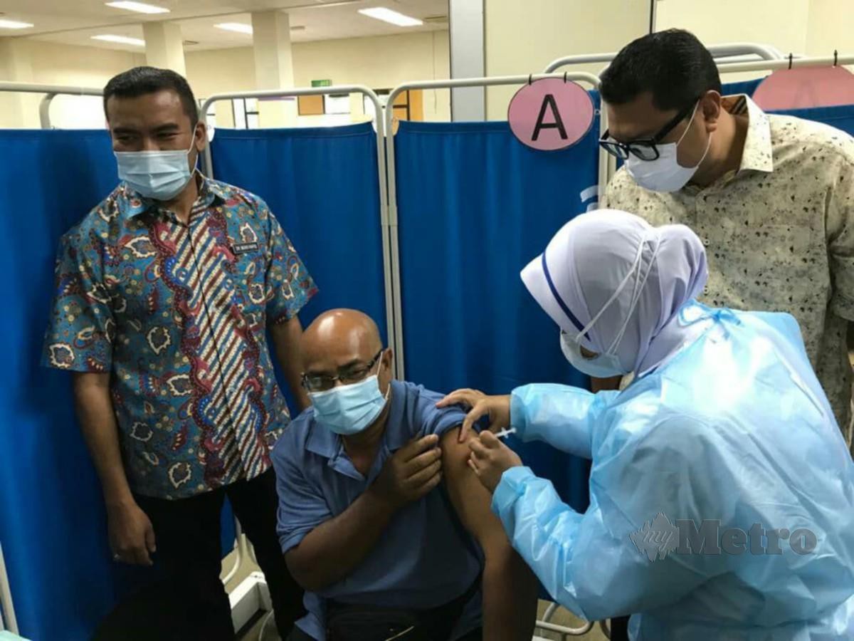 Dr Mohamad Rafiq (kiri) bersama Mohd Syahbuddin meneliti pemberian vaksin kepada seorang penduduk di PPV di Pusat Latihan kesedar. FOTO RAMLI IBRAHIM