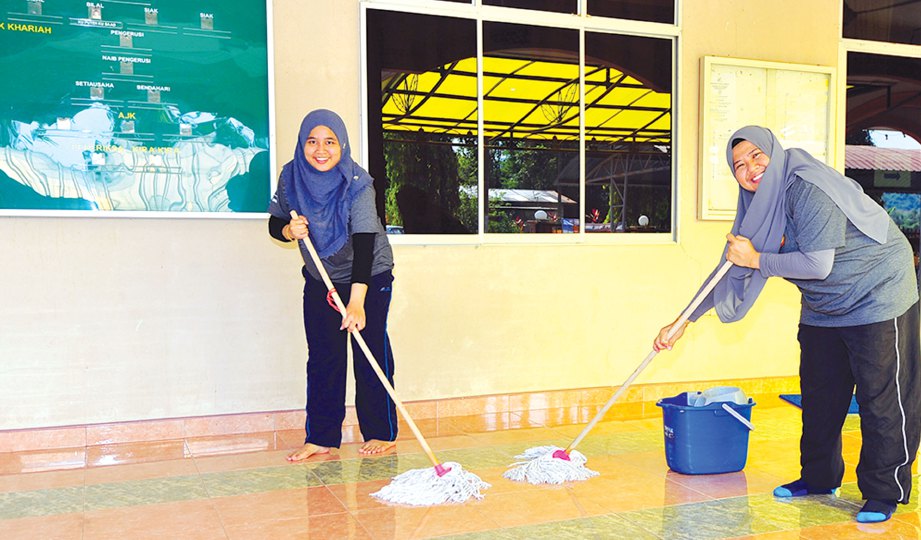 SEBAHAGIAN peserta bergotong-royong membersihkan sekitar pekarangan Masjid Kampung Darat. 