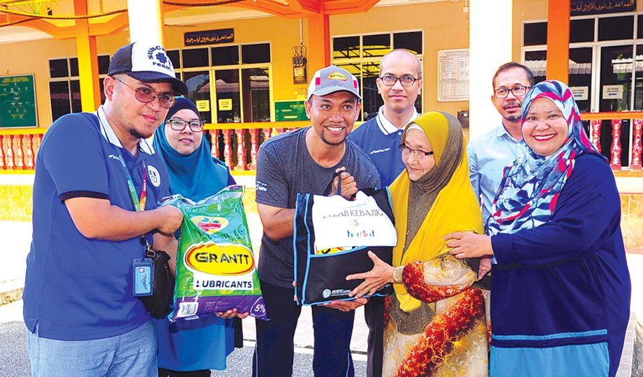 PENSYARAH Pusat Pengajian Antarabangsa (SoIS) Dr Mohd Haniff Jedin (tengah) menyampaikan sumbangan kepada penduduk di pekarangan Masjid Kampung Darat.