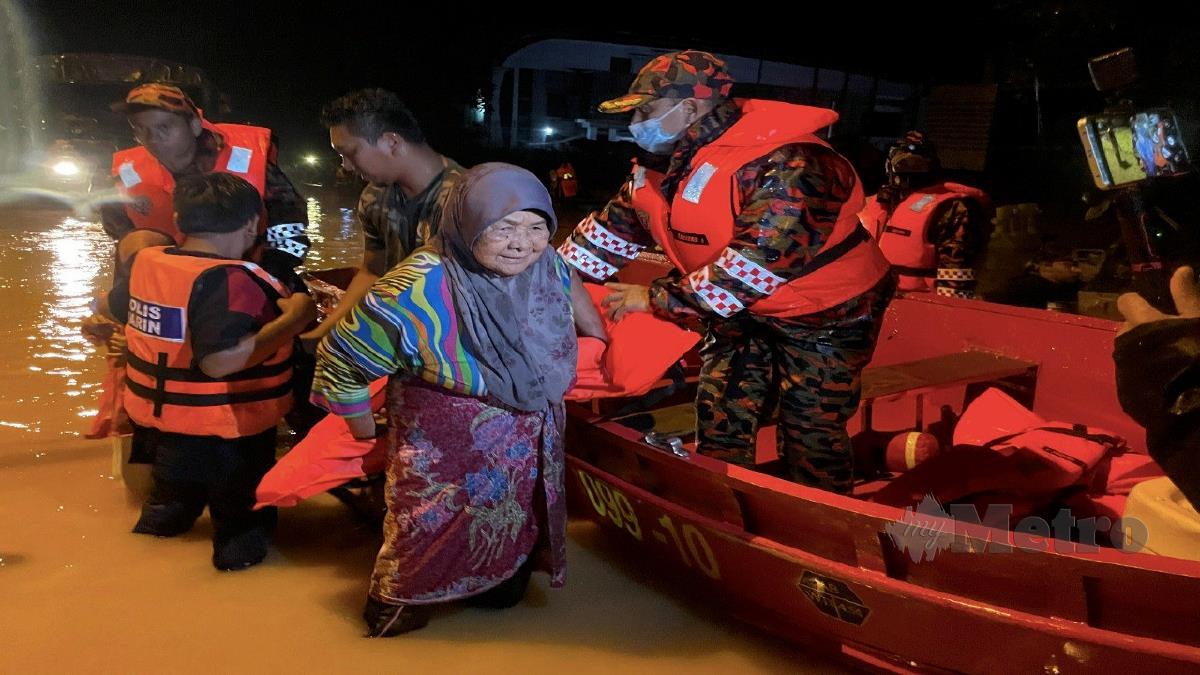 ANGGOTA bomba membantu menyelamatkan penduduk yang terperangkap dalam banjir di Kampung Paya Besar, Kuala Berang malam tadi. FOTO GHAZALI KORI