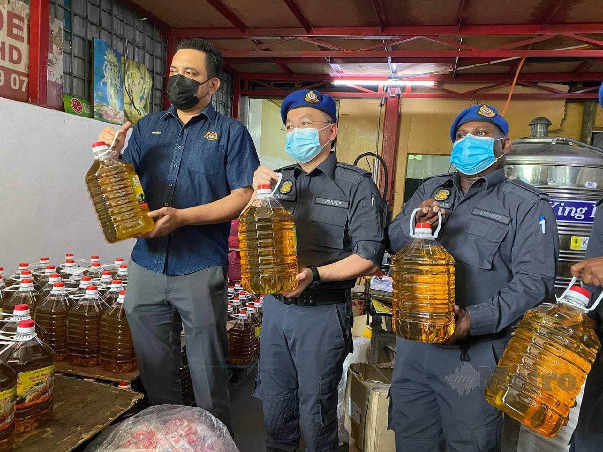  MOHD Ridzuan (kiri) menunjukkan minyak masak bersubsidi yang sudah dipindahkan ke dalam botol. FOTO Nur Izzati Mohamad