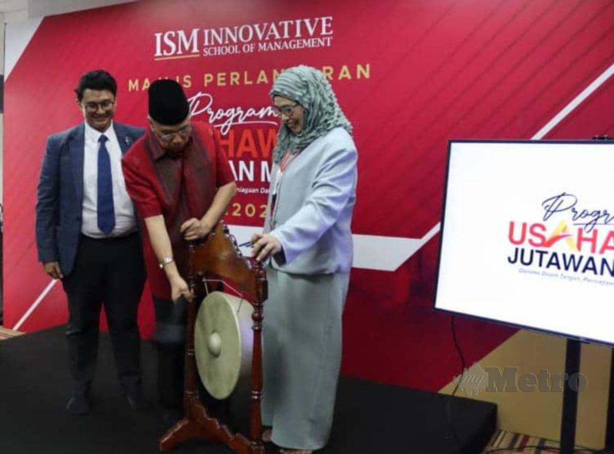 Dr Hashim mengetuk gong sebagai simbolik pelancaran Program Usahawan Jutawan Muda sambil disaksikan Shahawati Umar dan Amir Faisal.