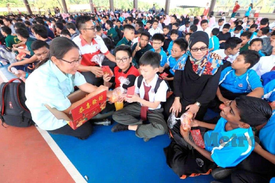 GURU SMK Semambu, Lim Pee Ing (kiri) dan Harnani Ahmad mengagihkan limau dan angpau kepada 653 pelajar sempena Tahun Baharu Cina. FOTO Mohd Rafi Mamat