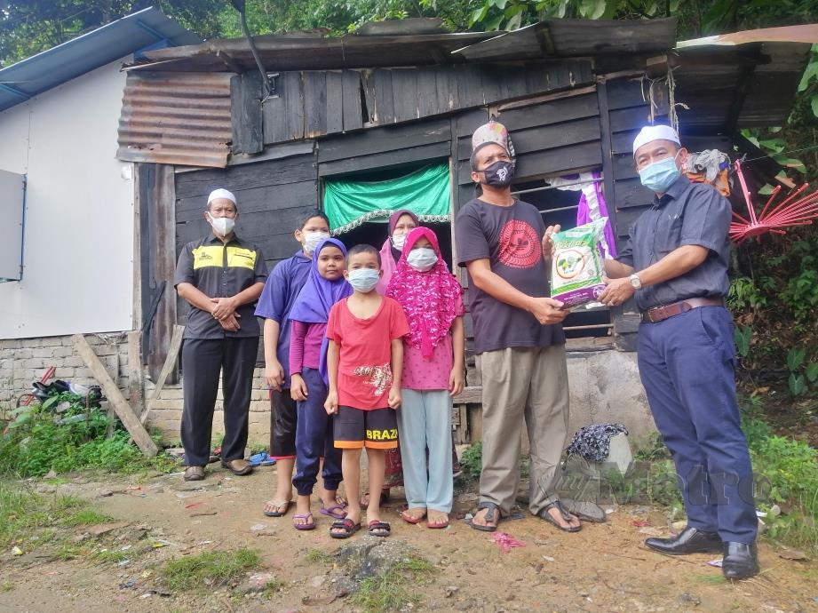 DR NOOR Azmi (kanan) menyerahkan bantuan awal kepada keluarga Mohd Shah Din di Kampung Bukit Putus, Gunong Semanggol yang ditimpa pokok. FOTO SHAIFUL SHAHRIN AHMAD PAUZI