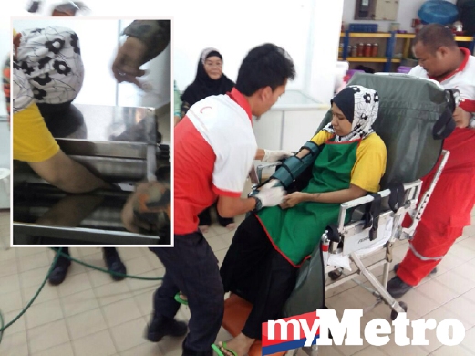 ANGGOTA paramedik merawat wanita yang tangannya tersepit pada mesin memproses makanan di tempat kejadian sebelum dibawa ke hospital. 