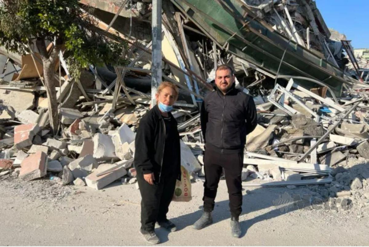 SERIZAN (kiri) bersama Ozhan berdiri di hadapan premis perniagaan mereka yang musnah akibat gempa bumi. FOTO Agensi 