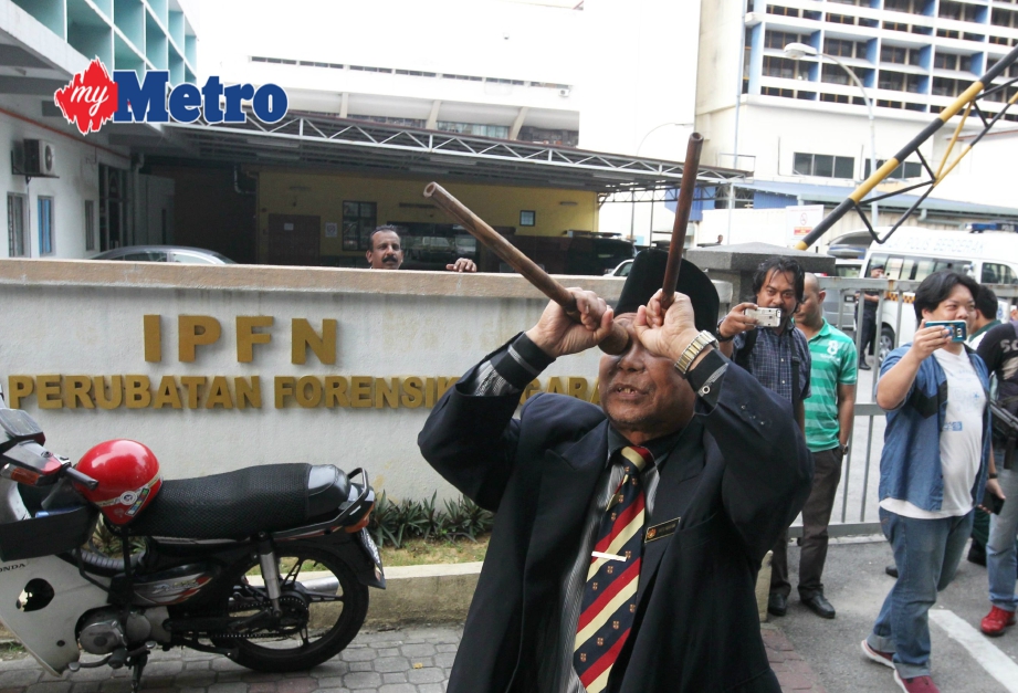 Aksi Ibrahim semasa melakukan ritual di hadapan Institut Perubatan Forensik Nasional, Hospital Kuala Lumpur pada 13 Mac lalu menggunakan buluh sebagai teropong kononnya supaya mayat Kim Jong-nam dihantar pulang. FOTO Yazit Razali