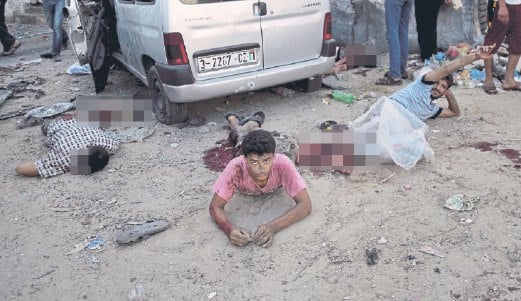 GAMBAR fail menunjukkan seorang lelaki Palestin menanti pertolongan sementara beberapa rakannyaterbunuh dalam serangan Israel di kejiranan Shijaiyah, tahun lalu.