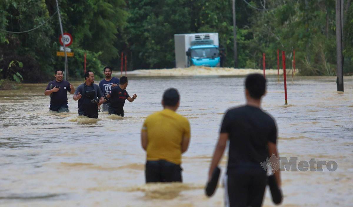 PENDUDUK meredah banjir di Kampung Chalok Kedai. FOTO Ghazali Kori
