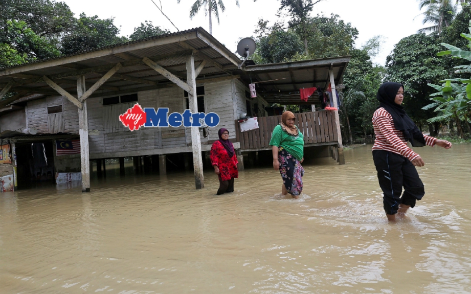 (Dari kanan) Ayu Wati Sarina Alimudin, 16, Siti Rokiah Che Awang, 46, dan Nik Nap Che Mat, 53, pulang ke rumah selepas air mulai surut di Kampung Tasek, Permaisuri. FOTO Ghazali Kori 