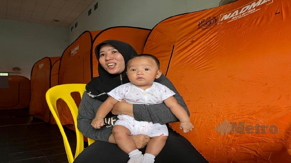 NUR Ashiqin  bersama anak bongsunya, Tengku Putra Sulaiman berusia empat bulan ketika ditemui di pusat pemindahan sementara Dewan Orang Ramai Kampung Shukor. FOTO ZATUL IFFAH ZOLKIPLY
