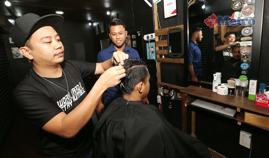 FARHAN memerhatikan pekerja menggunting rambut pelanggan.   FOTO Owee Ah Chun